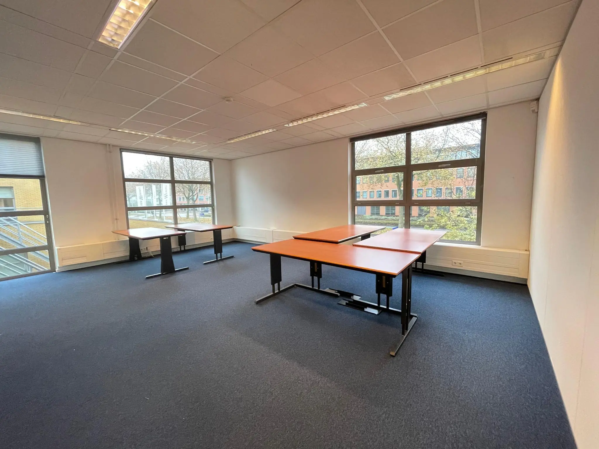 Kantoorruimte aan de Rivium 3e Straat met grote ramen en enkele verstelbare bureaus.